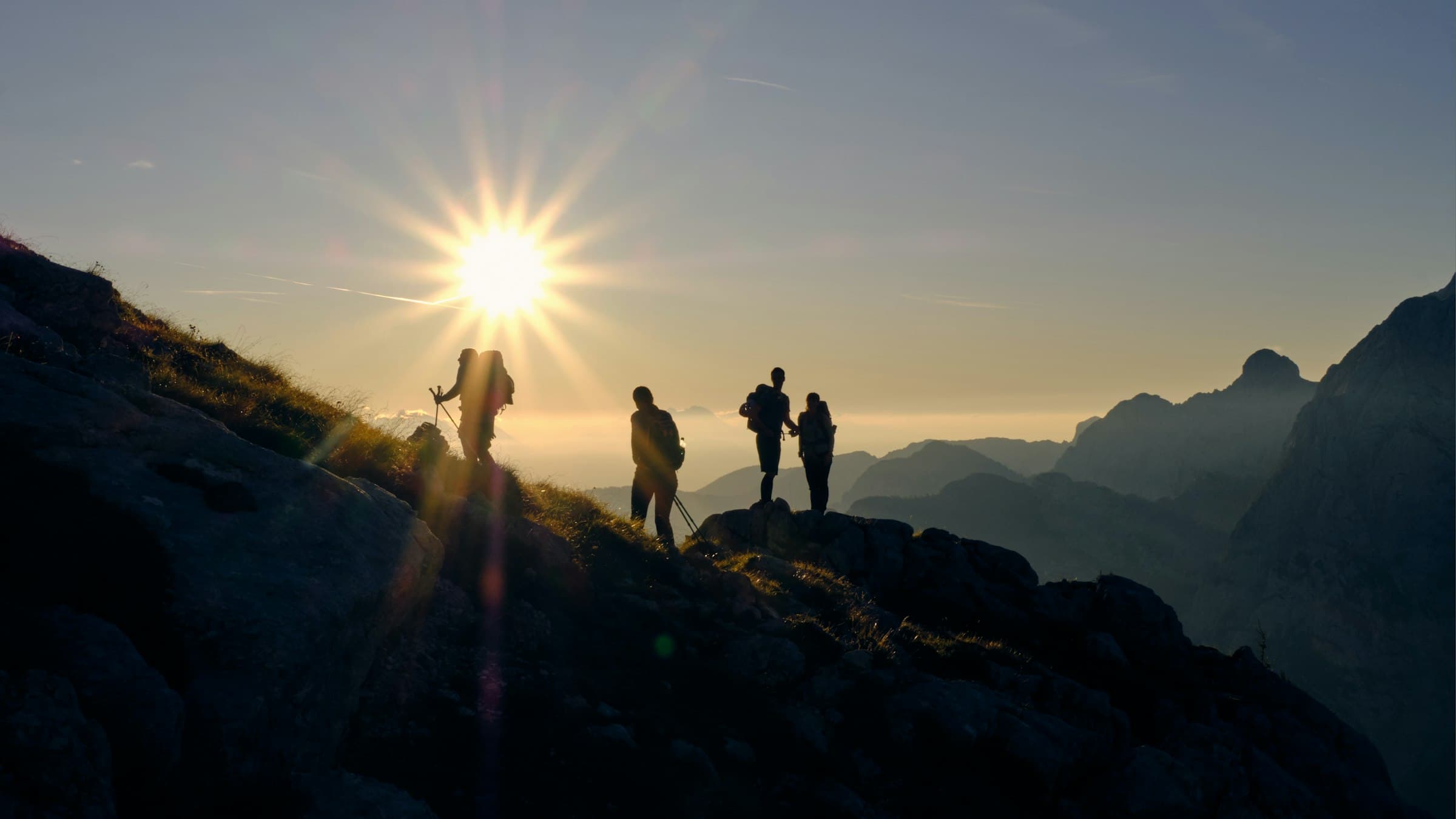 Group of hikers silhouetted on a ridge at sunrise