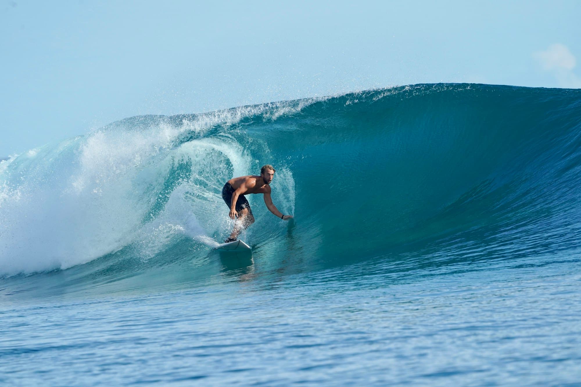 Surfer riding inside a turquoise barrel wave