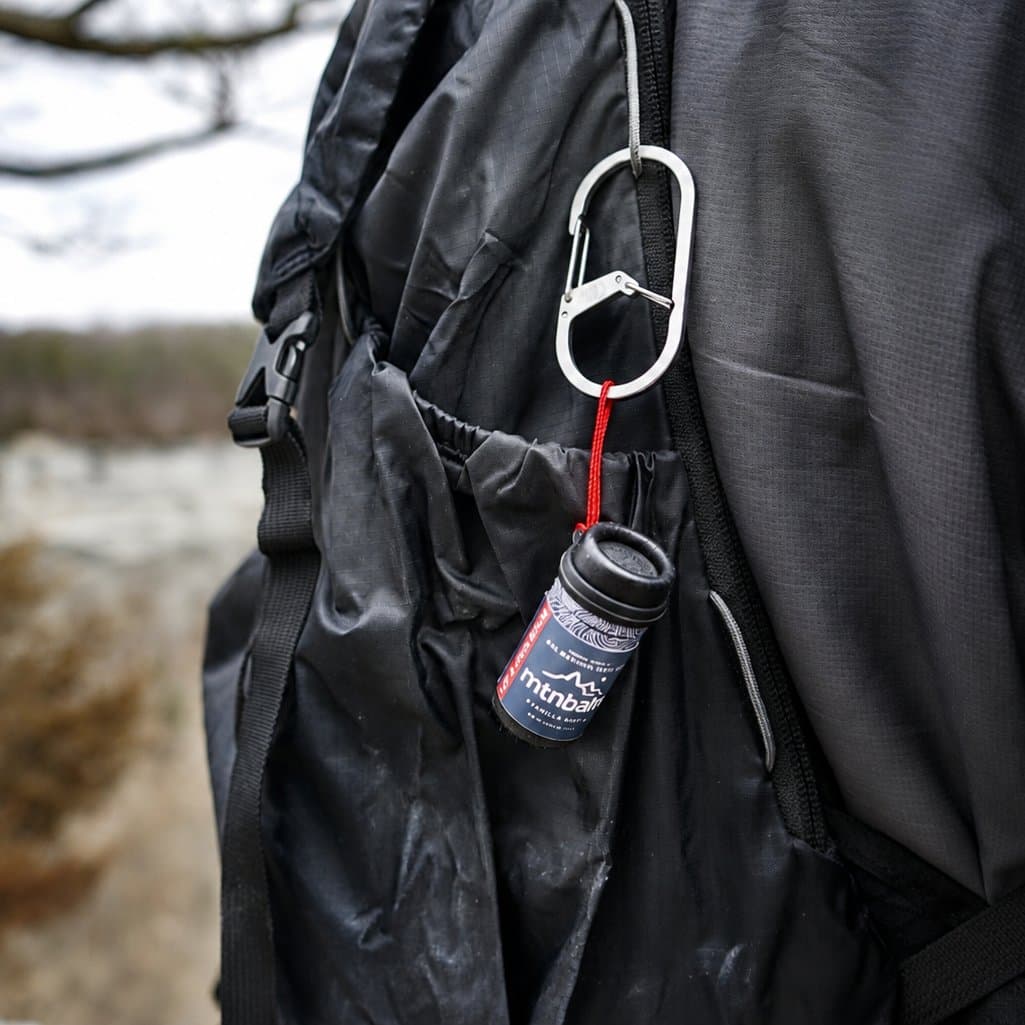 Summit Stick clipped to a backpack with a carabiner